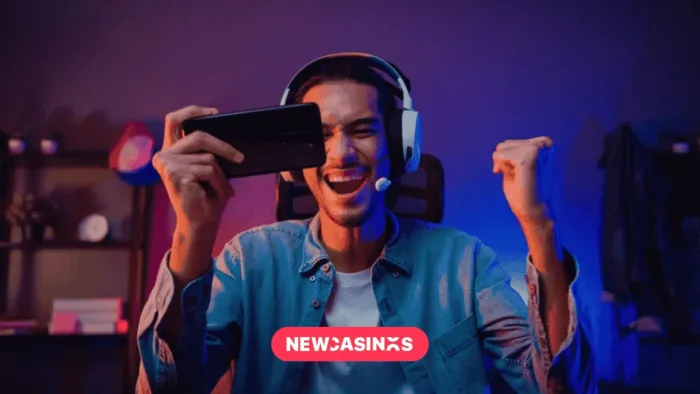 Exploring the Rise of Mobile Gaming Penetration in the UK Gamer wearing headphones playing video game online with smartphone, alongside a 'NEWCASINOS' logo in pink.