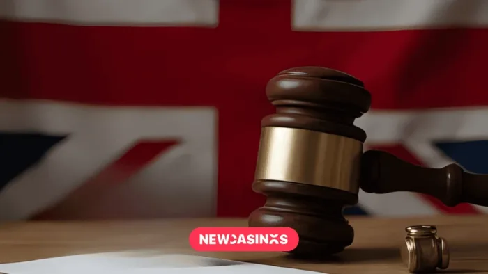 TGP Europe Exits UK Market After £3.3M Gambling Commission Fine A wooden gavel with a gold band rests on a wooden surface, symbolizing legal authority, with a blurred Union Jack flag in the background. A small coin and a piece of paper are also visible, alongside a 'NEWCASINOS' logo in pink.