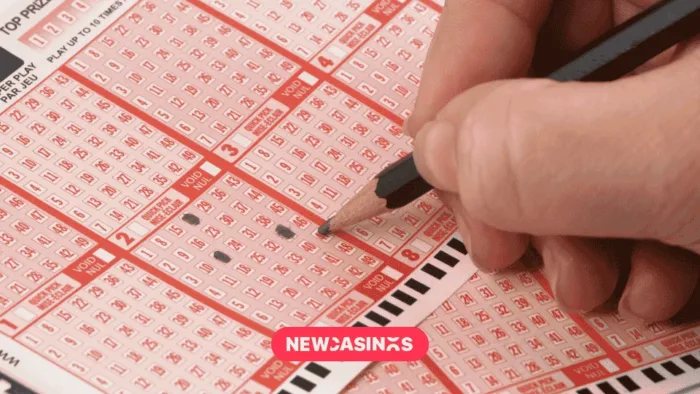 UK National Lottery and Digital Push Lift Allwyn’s Q1 Results a hand holding a pencil while crossing out options on a lottery slip