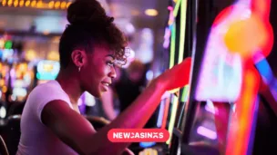 The Hidden Maths Behind Progressive Jackpots and Why It Matters A woman smiling while playing a brightly lit slot machine in a casino, surrounded by colorful lights and gaming machines.