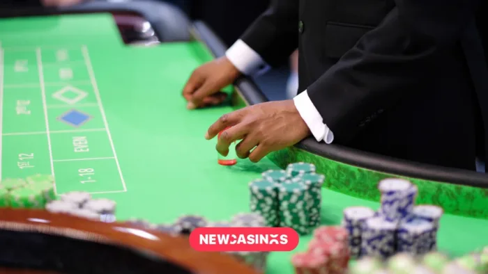 A poker player's hands placing chips on a felt green table.