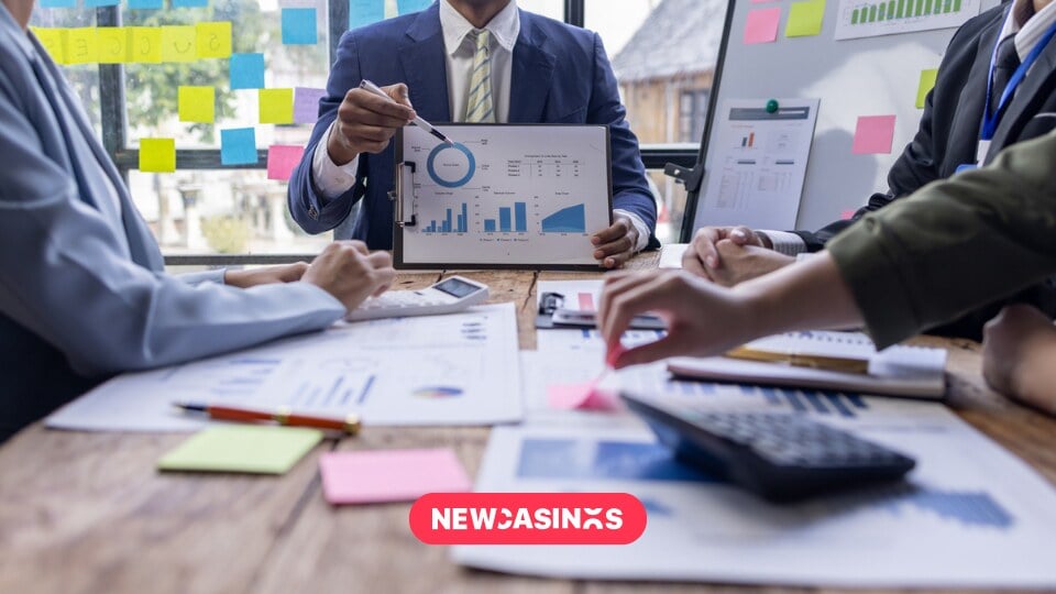 Business people sat at a meeting table, discussing graphs and charts.