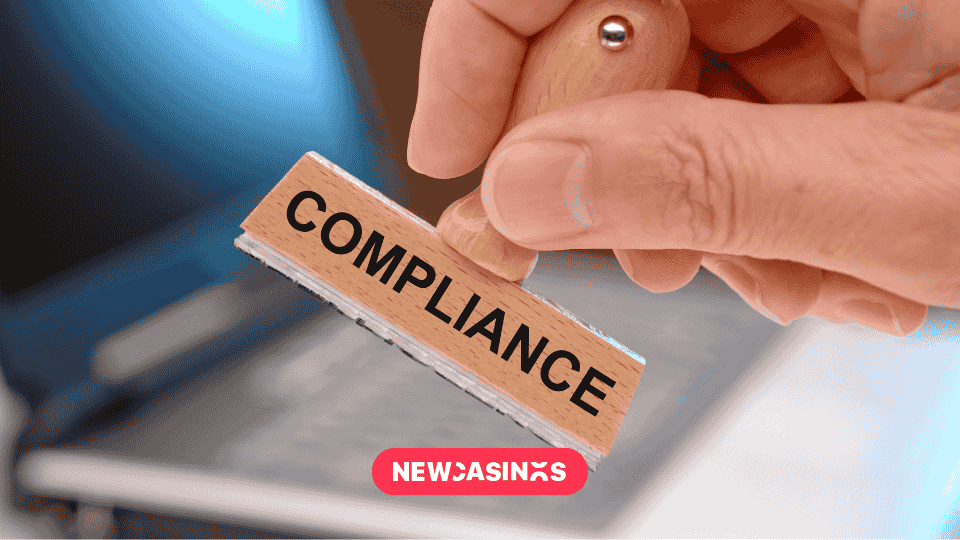 a hand holding a rubber stamp with "COMPLIANCE" text, positioned above paperwork or documents