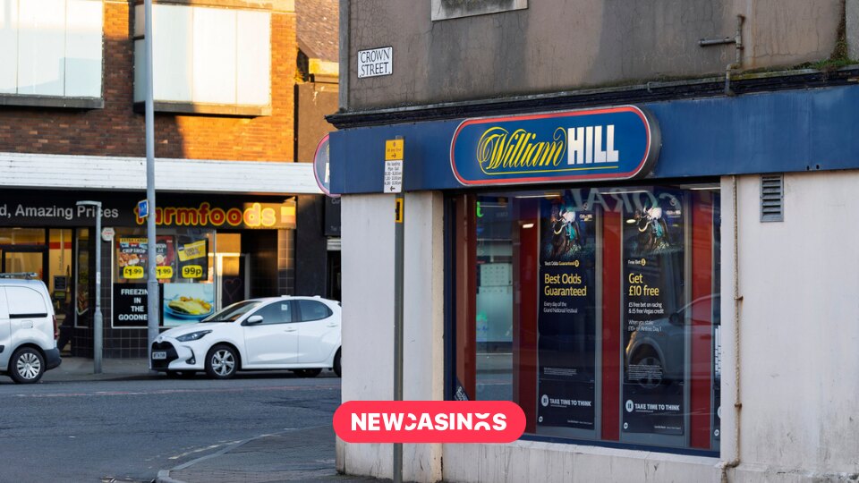 Exterior William Hill betting shop in a high street. The New Casinos logo in the foreground.