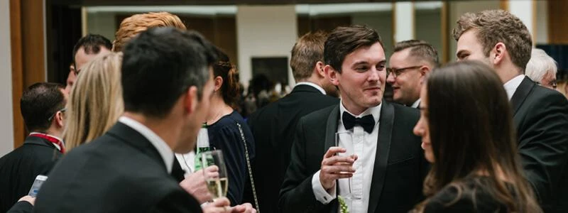 Smartly dressed group drinking wine at a formal occasion.